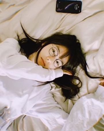 唐田えりかがメガネをかけてベッドで横になっている写真画像